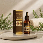 Hoegoa Hair Growth Hair Serum 5% Biotin in an amber glass dropper bottle next to its brown and gold packaging box, styled on a round tray with a rolled towel and green foliage.