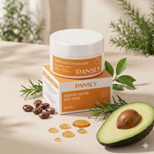 Pansly Keratin & Biotin Hair Mask jar and box stacked together on a warm beige surface, styled with rosemary sprigs, coffee beans, honey droplets, and a sliced avocado.